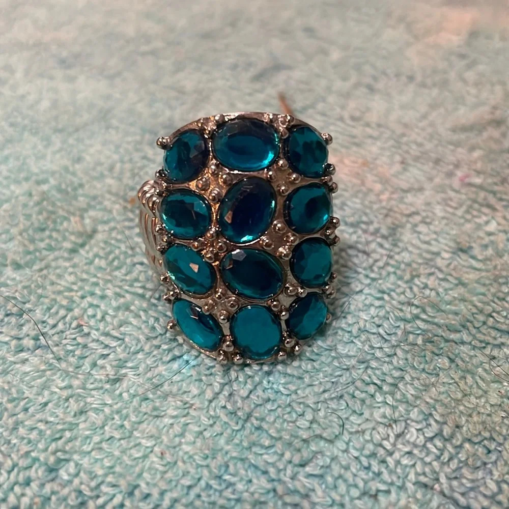 Adjustable, blue stones set in metal ring.